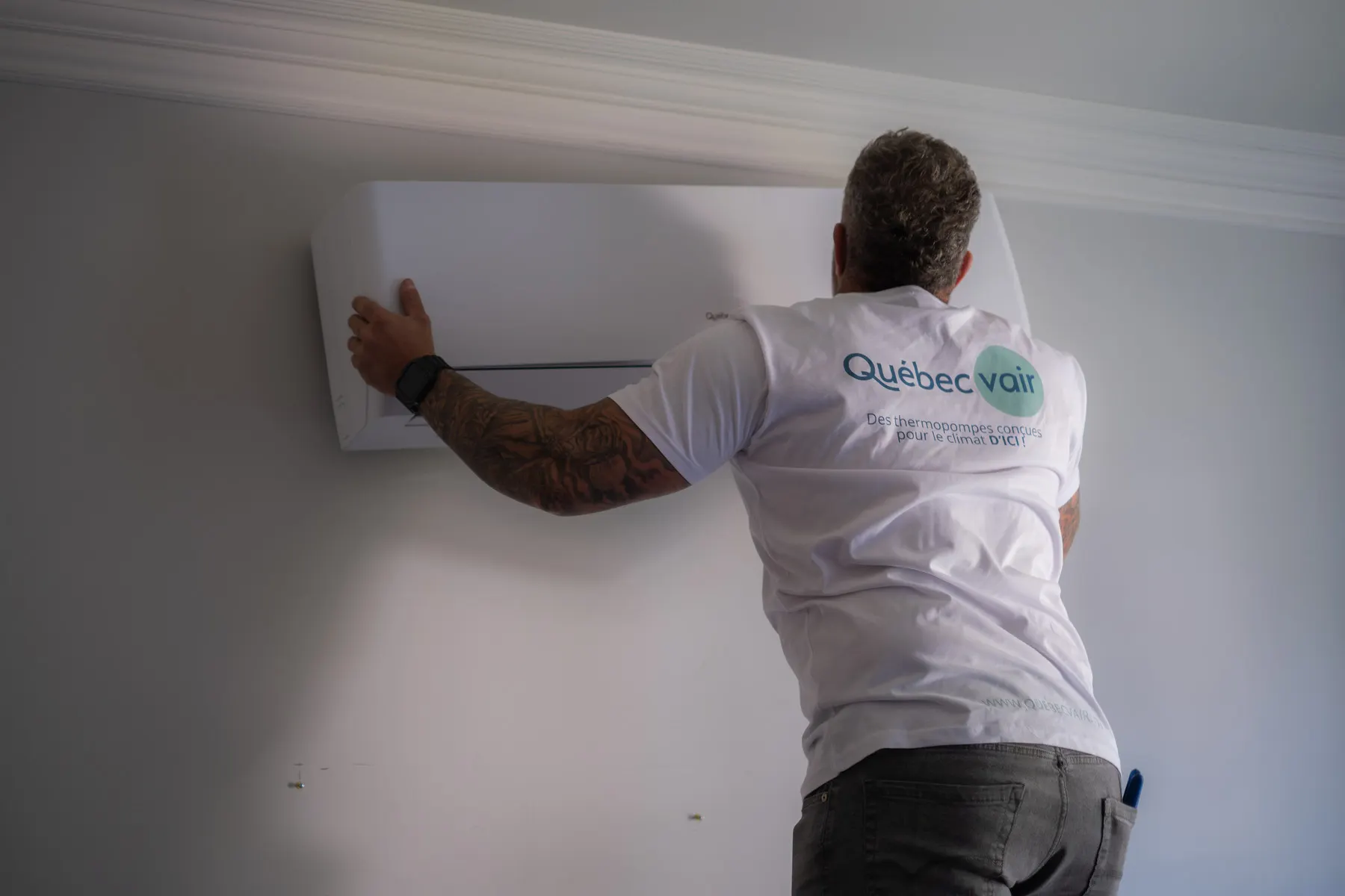 Un technicien installe l’unité intérieure d’une thermopompe murale près du plafond